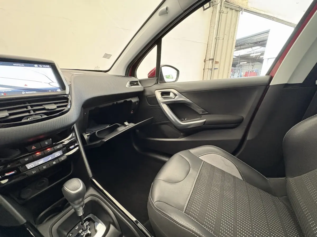 Intérieur côté passager du Peugeot 2008 rouge 2019, avec tableau de bord tactile et siège en cuir noir.