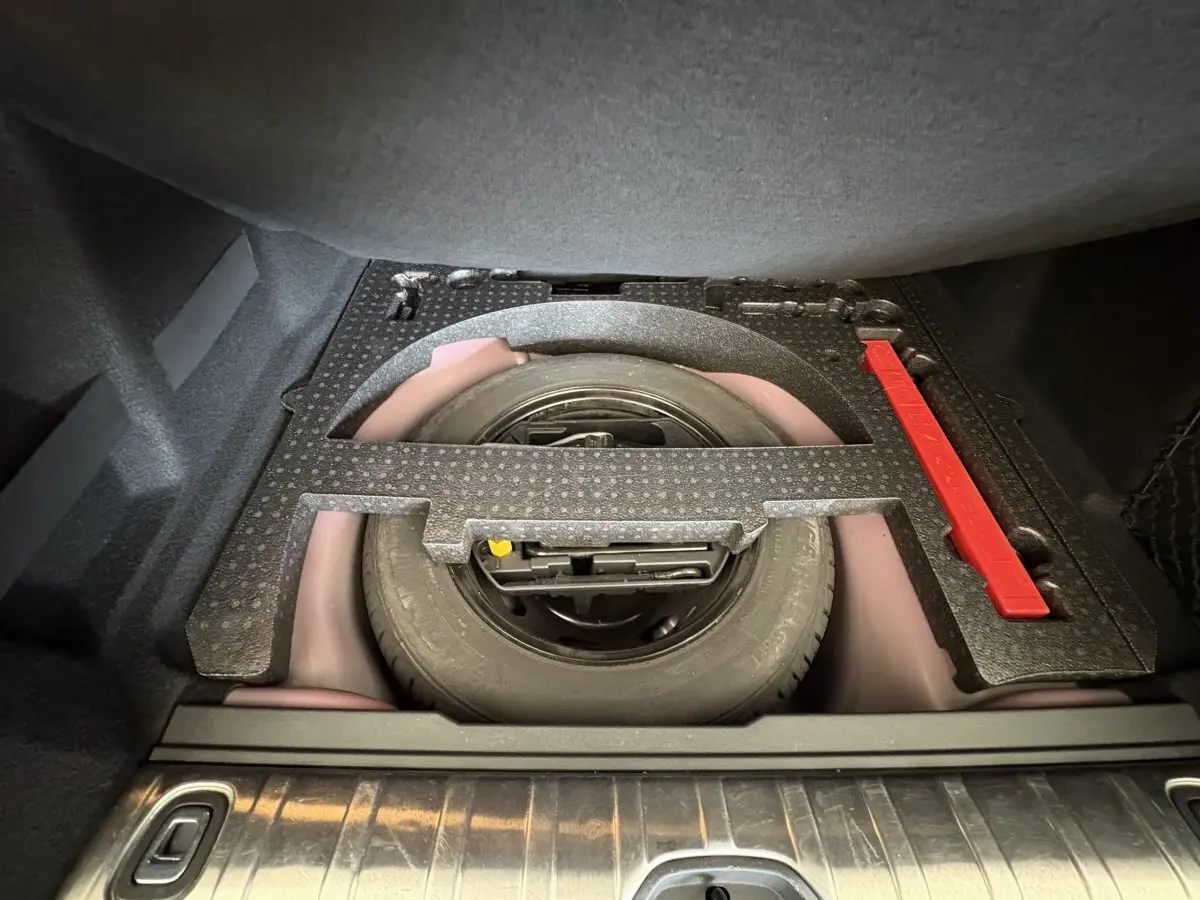 Vue plongeante sur la roue de secours et le rangement sous tablette du coffre du Peugeot 2008 rouge 2019.