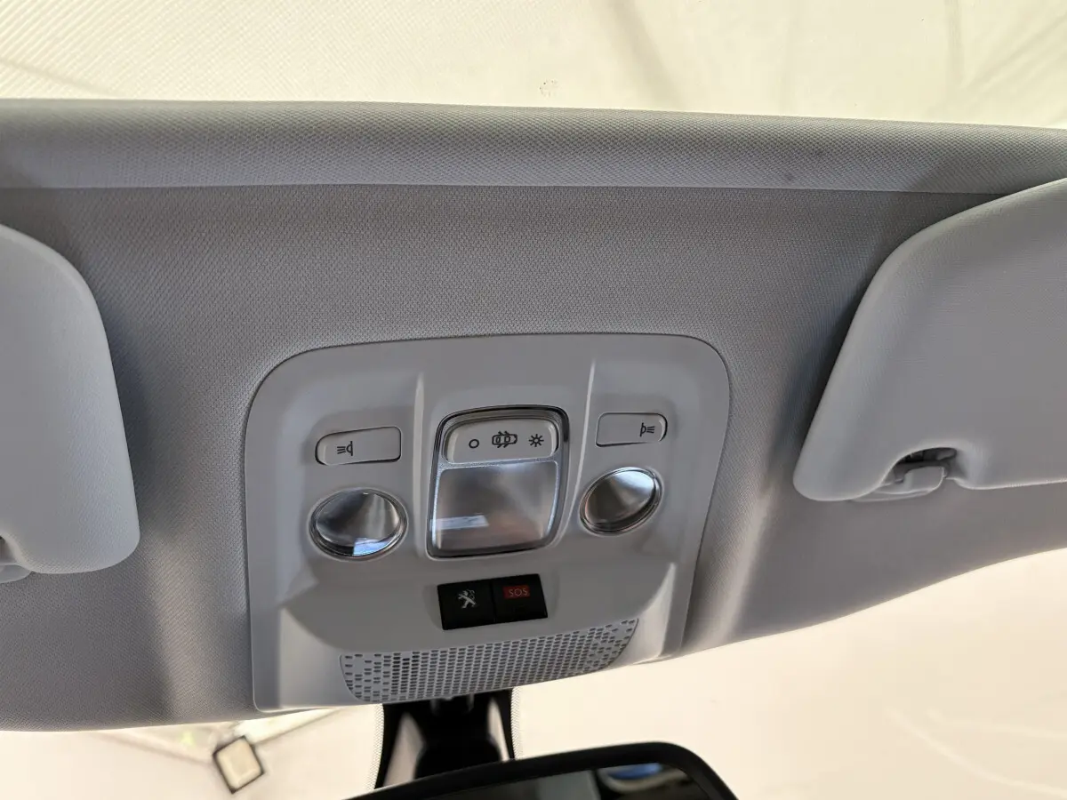 Vue en gros plan du plafonnier gris clair avec commandes d'éclairage et bouton SOS dans un Peugeot 2008 rouge
