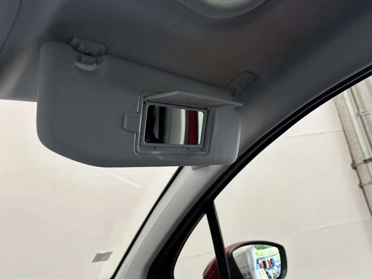 Miroir de courtoisie ouvert sur pare-soleil côté conducteur dans l'habitacle d'un Peugeot 2008 rouge 2019.