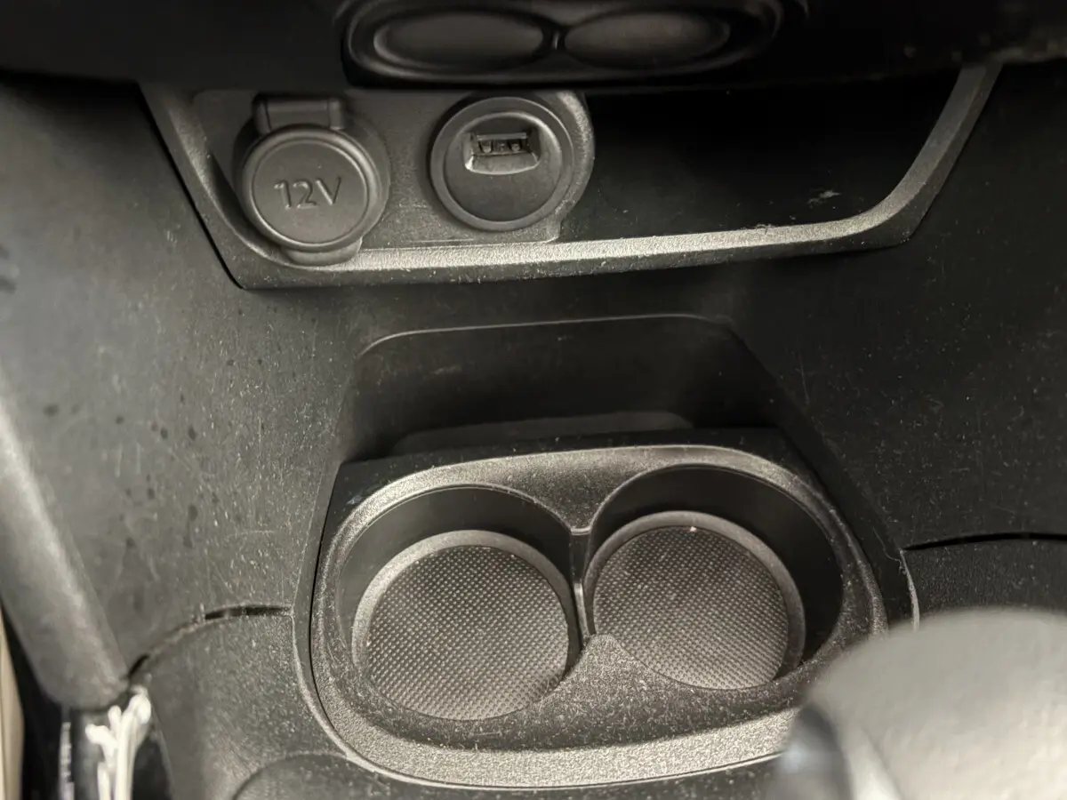 Gros plan sur les porte-gobelets noirs et prise 12V dans l'habitacle du Peugeot 2008 Puretech rouge 2019