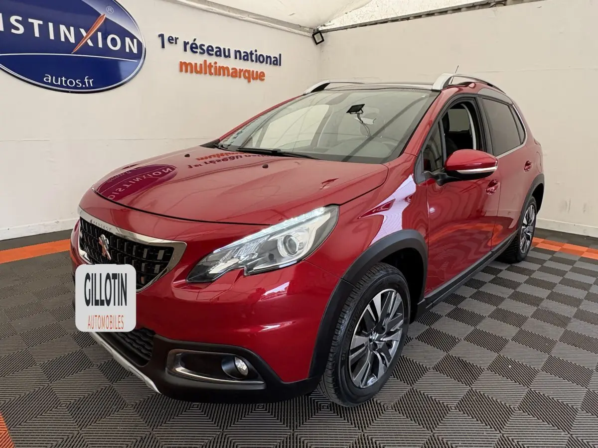 Peugeot 2008 rouge vue 3/4 avant droit en intérieur, avec phares LED et jantes alliage distinctives.