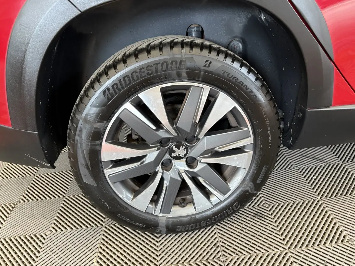 Gros plan sur la roue avant droite d’un Peugeot 2008 rouge, avec jante alliage et pneu Bridgestone Turanza.