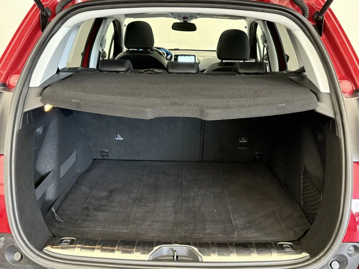 Coffre ouvert d'un Peugeot 2008 rouge 2019, vue arrière montrant l'espace de chargement avec tablette de protection.