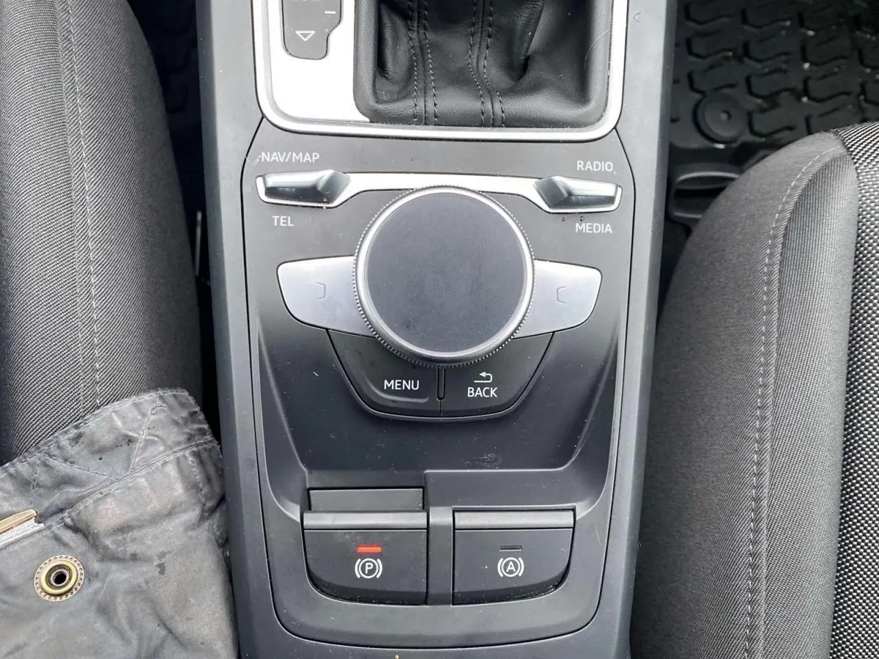 Vue plongeante sur la console centrale noire de l'Audi Q2 2023, avec molette MMI et commandes électroniques visibles.