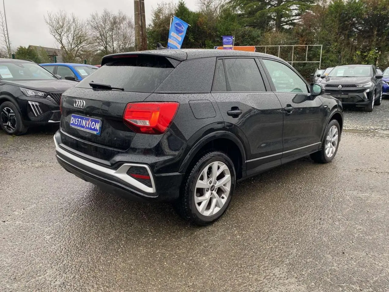 Audi Q2 noir vue 3/4 arrière droit, hayon électrique et jantes alliage visibles sous un ciel couvert.