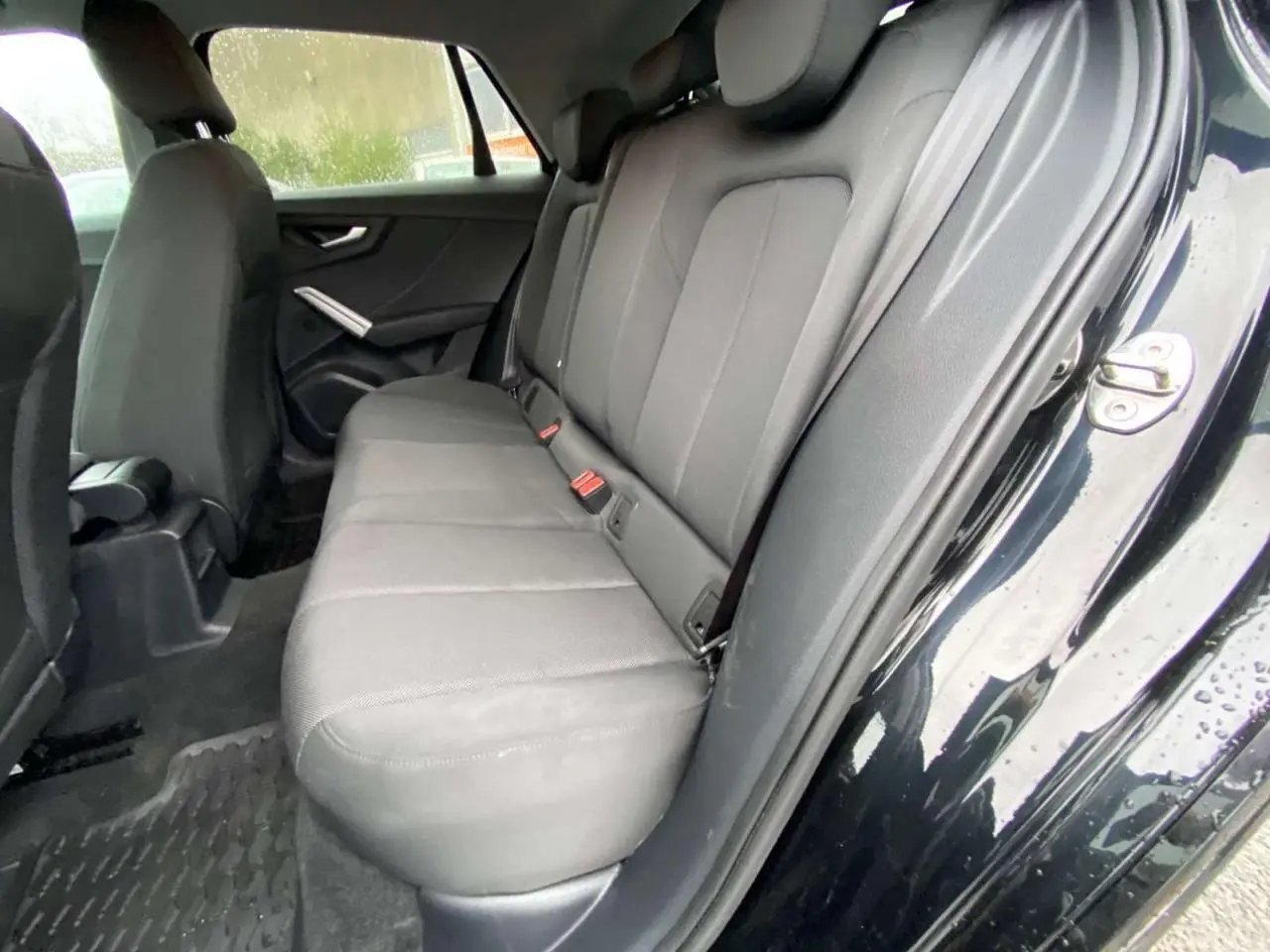 Vue intérieure côté droit sur la banquette arrière grise d’un Audi Q2 noir 2023 avec porte ouverte.