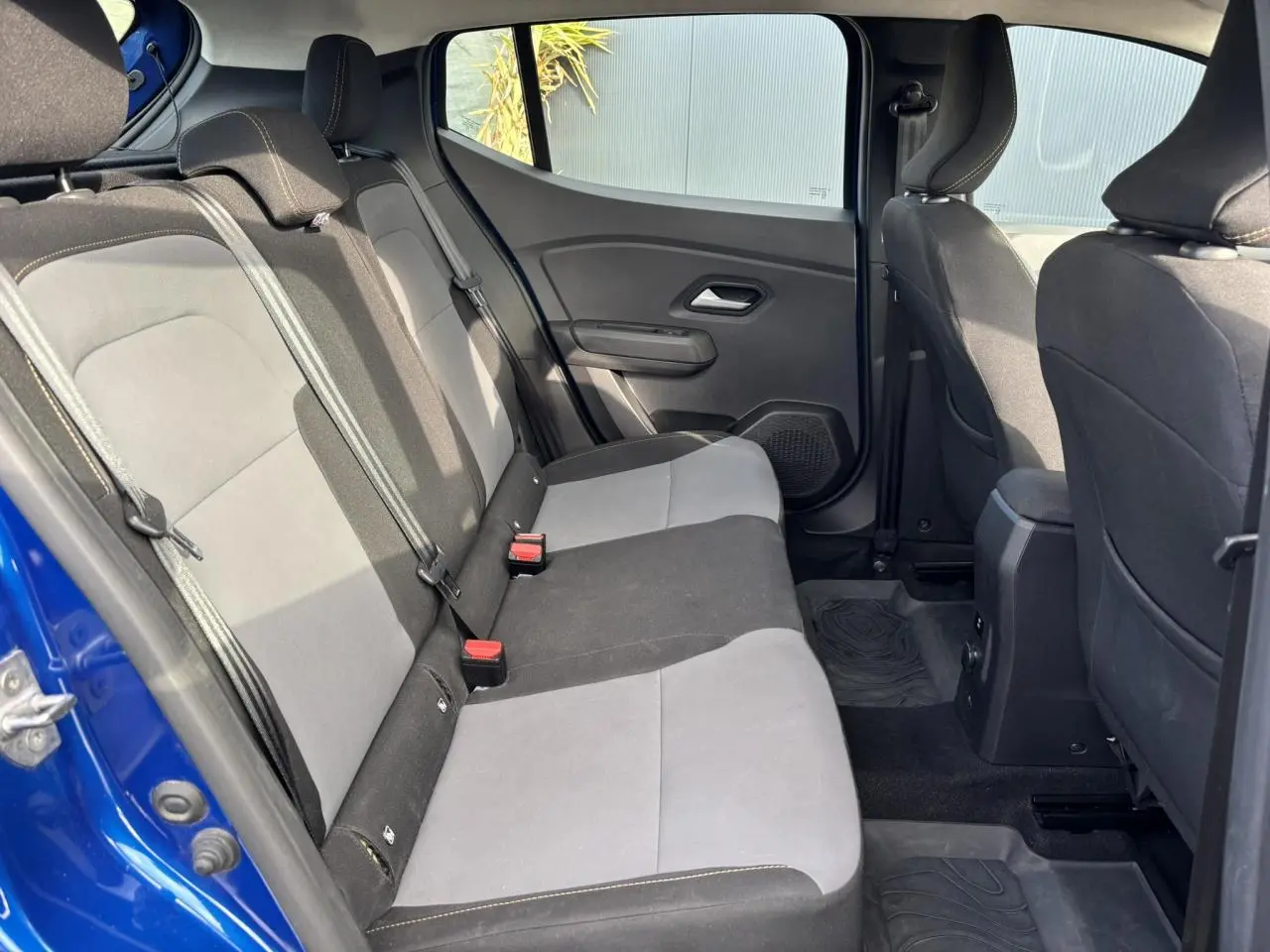 Vue intérieure arrière côté gauche du Dacia Sandero Stepway 2025 Bleu Iron, montrant les sièges bicolores et les ceintures de sécurité.