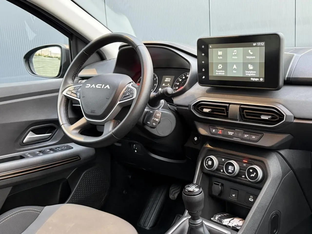 Vue intérieure côté conducteur du tableau de bord et volant Dacia avec écran tactile 8 pouces et commandes au volant.