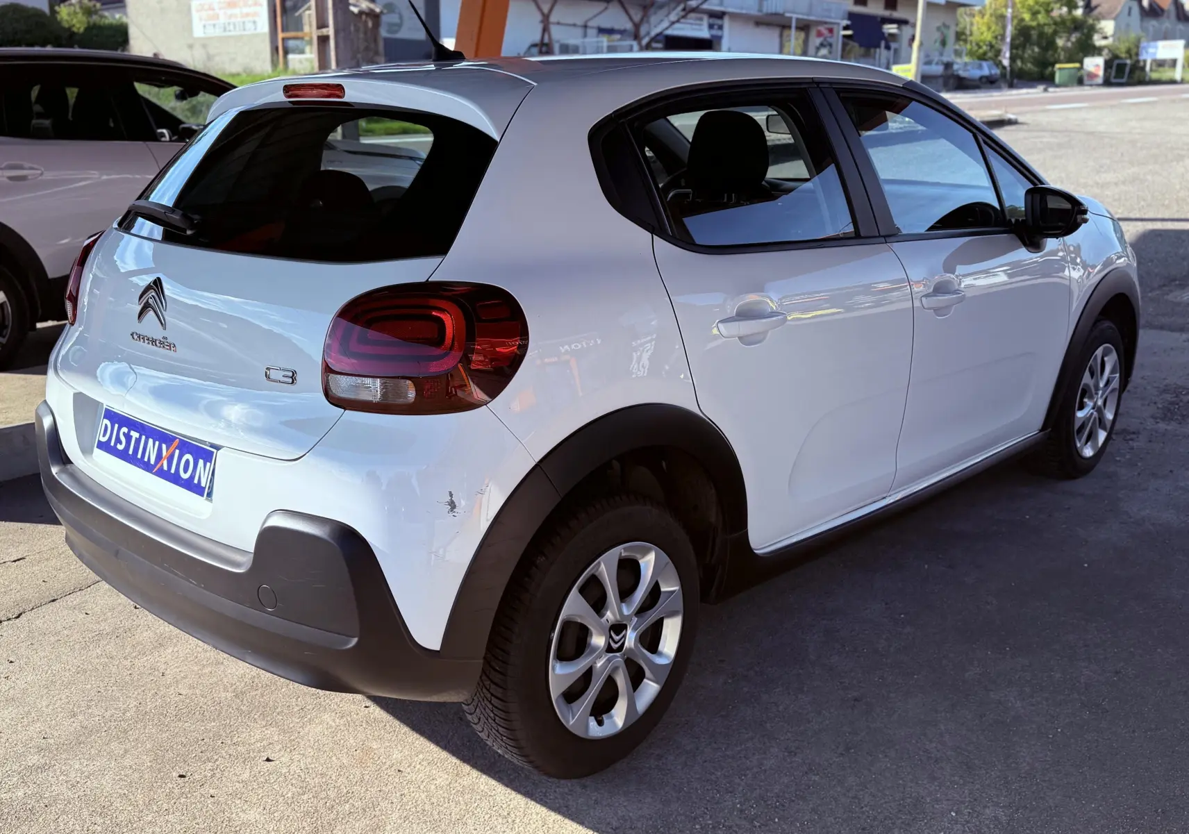 Citroën C3 blanche vue en 3/4 arrière droit, avec feux arrière foncés et jantes alliage argentées.