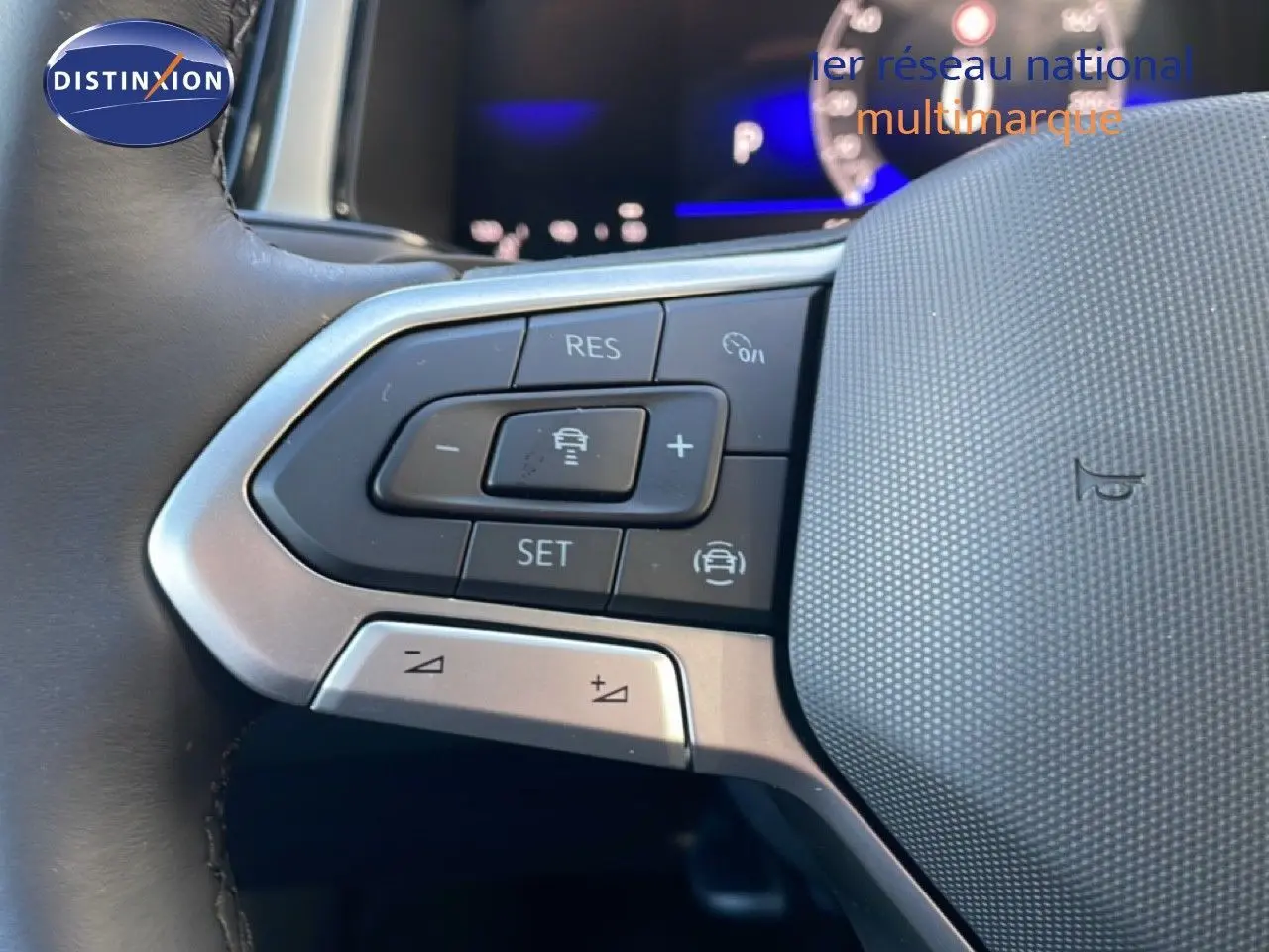 Gros plan sur les commandes au volant du Volkswagen T-Roc gris pyrite, mettant en valeur les boutons de régulateur de vitesse.