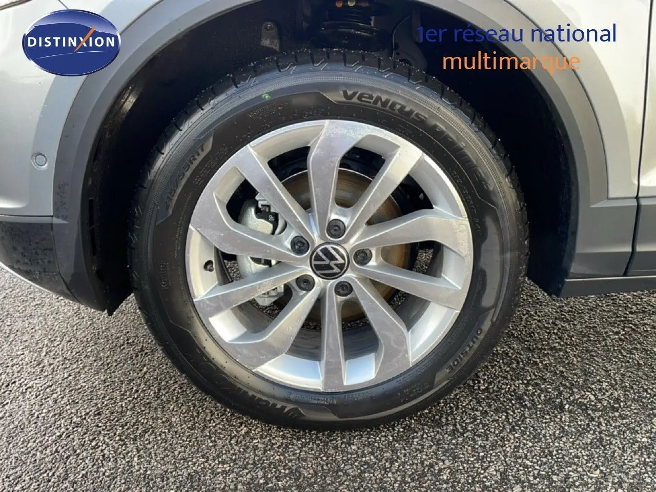 Gros plan sur la roue avant gauche du Volkswagen T-Roc gris pyrite métal, mettant en valeur la jante alliage et le pneu.