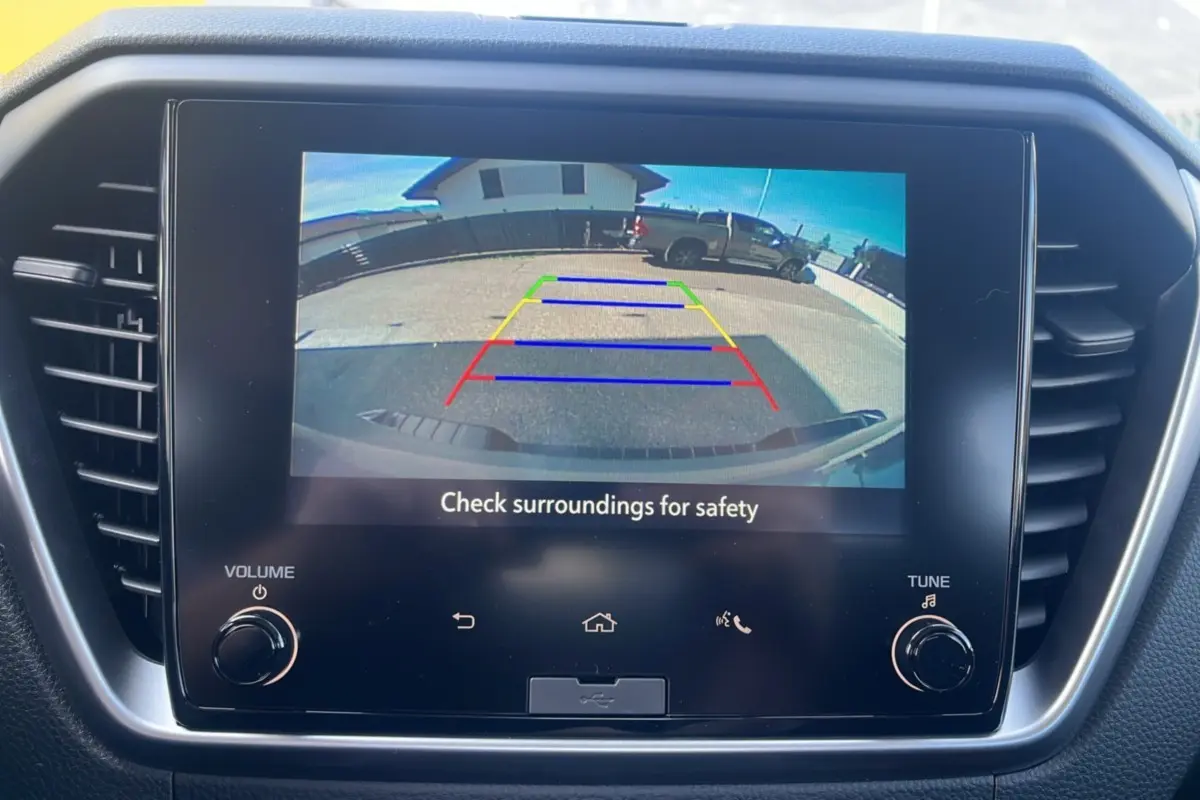 Écran tactile intérieur montrant la caméra de recul avec vue arrière sur un Isuzu D-MAX gris Kinabalu en stationnement.