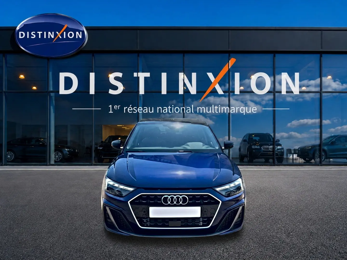 Vue avant d'une Audi A1 Sportback 30 TFSI 116 S line bleu foncé avec calandre hexagonale et phares LED devant un showroom Distinxion.