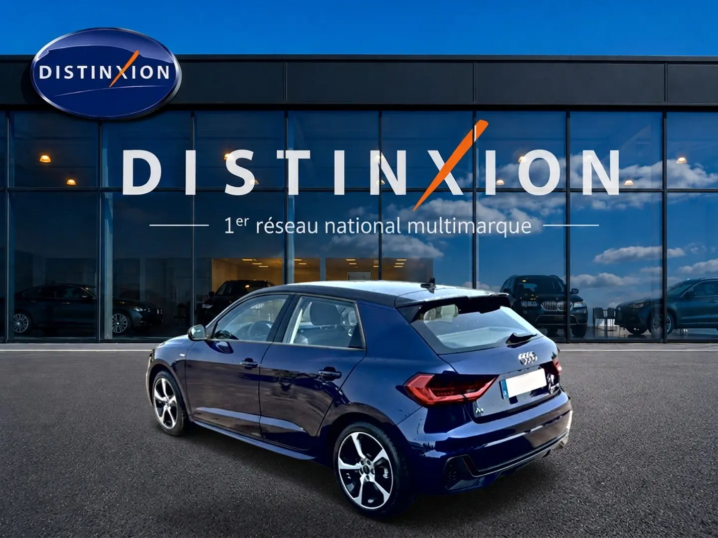 Audi A1 Sportback bleu foncé vue 3/4 arrière droit, avec jantes alliage et becquet arrière sportif.