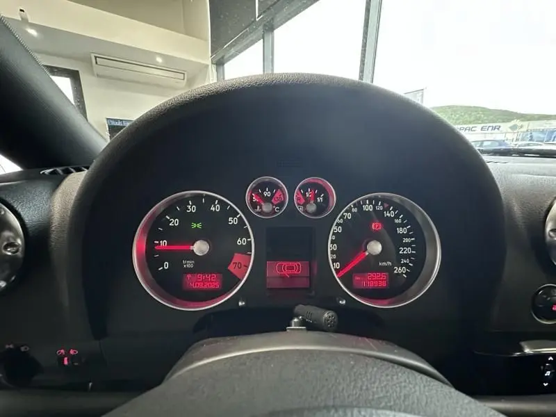 Vue intérieure du tableau de bord de l'Audi TT Coupé noir 2002, avec compteurs analogiques et affichage numérique rouge.