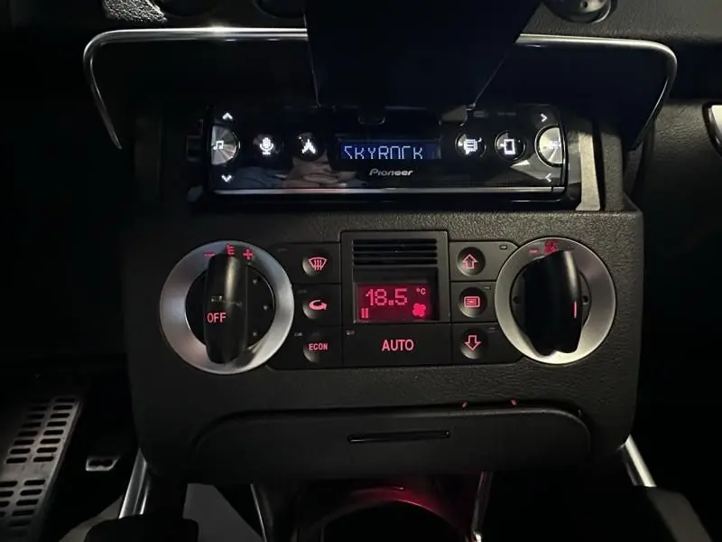 Vue rapprochée du tableau de bord noir de l'Audi TT Coupé 2002, mettant en valeur la climatisation automatique et l'autoradio Pioneer.