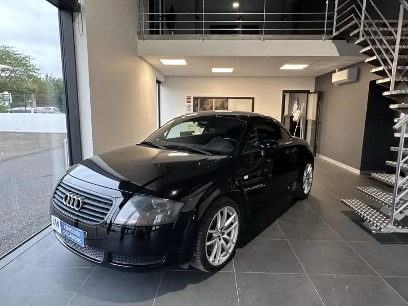 Audi TT Coupé noir de 2002 vu en 3/4 avant droit, exposé en intérieur avec jantes argentées et calandre distinctive.