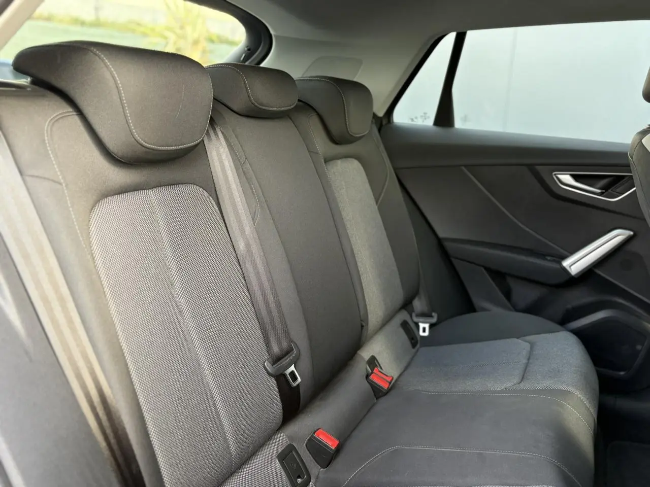 Vue intérieure côté droit des sièges arrière gris foncé de l'Audi Q2 30 TDI S-Line 2025 avec ceintures et appuie-têtes.