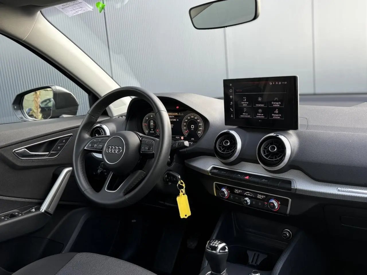 Vue intérieure côté conducteur de l'Audi Q2 30 TDI S-Line 2025, tableau de bord noir avec écran MMI et volant cuir multifonction.