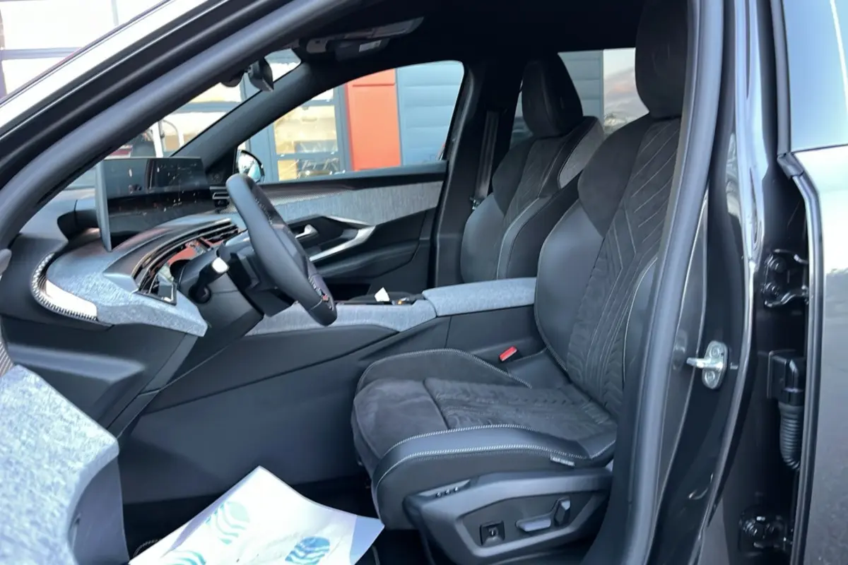 Intérieur côté conducteur du Peugeot 5008 Hybrid 2025, sièges Alcantara noirs et tableau de bord gris clair.