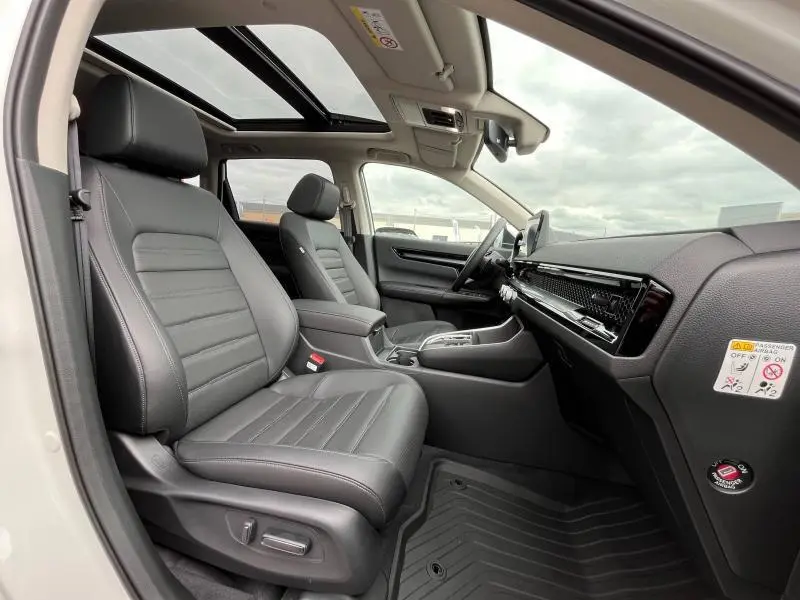 Vue intérieure côté conducteur du Honda CR-V 2024 blanc platine avec sièges cuir noirs et toit panoramique en verre.