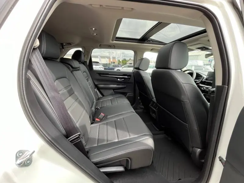 Vue intérieure côté gauche du Honda CR-V blanc platine nacré 2024, montrant les sièges arrière en cuir noir et toit panoramique.