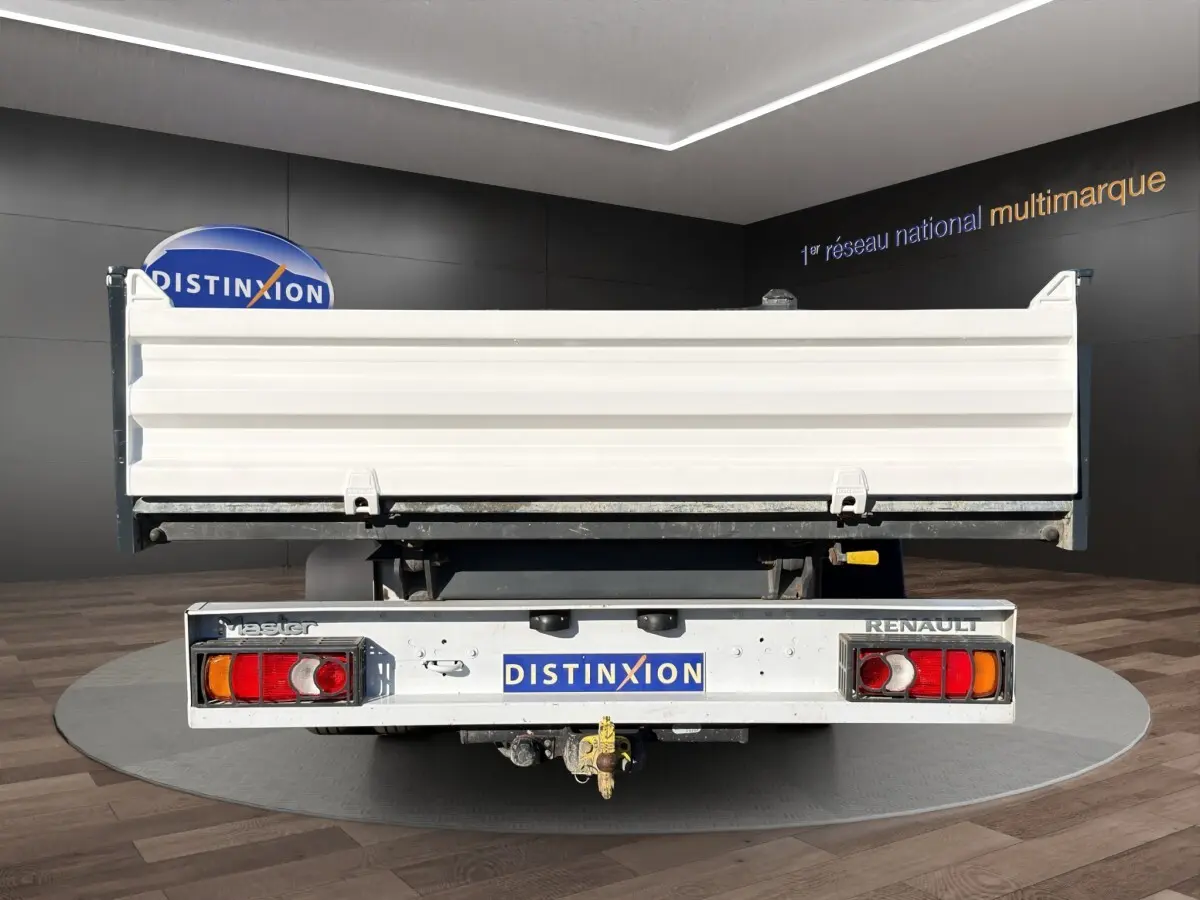 Vue arrière d’un utilitaire Renault Master blanc avec benne et attelage visible en intérieur showroom.