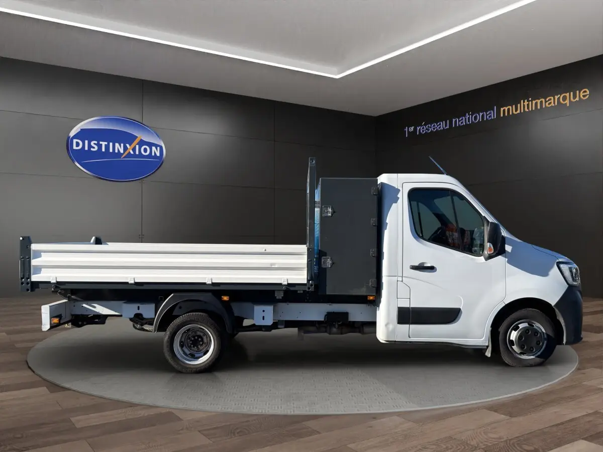 Renault Master blanc vu de profil côté droit, avec benne arrière et cabine simple dans un showroom.