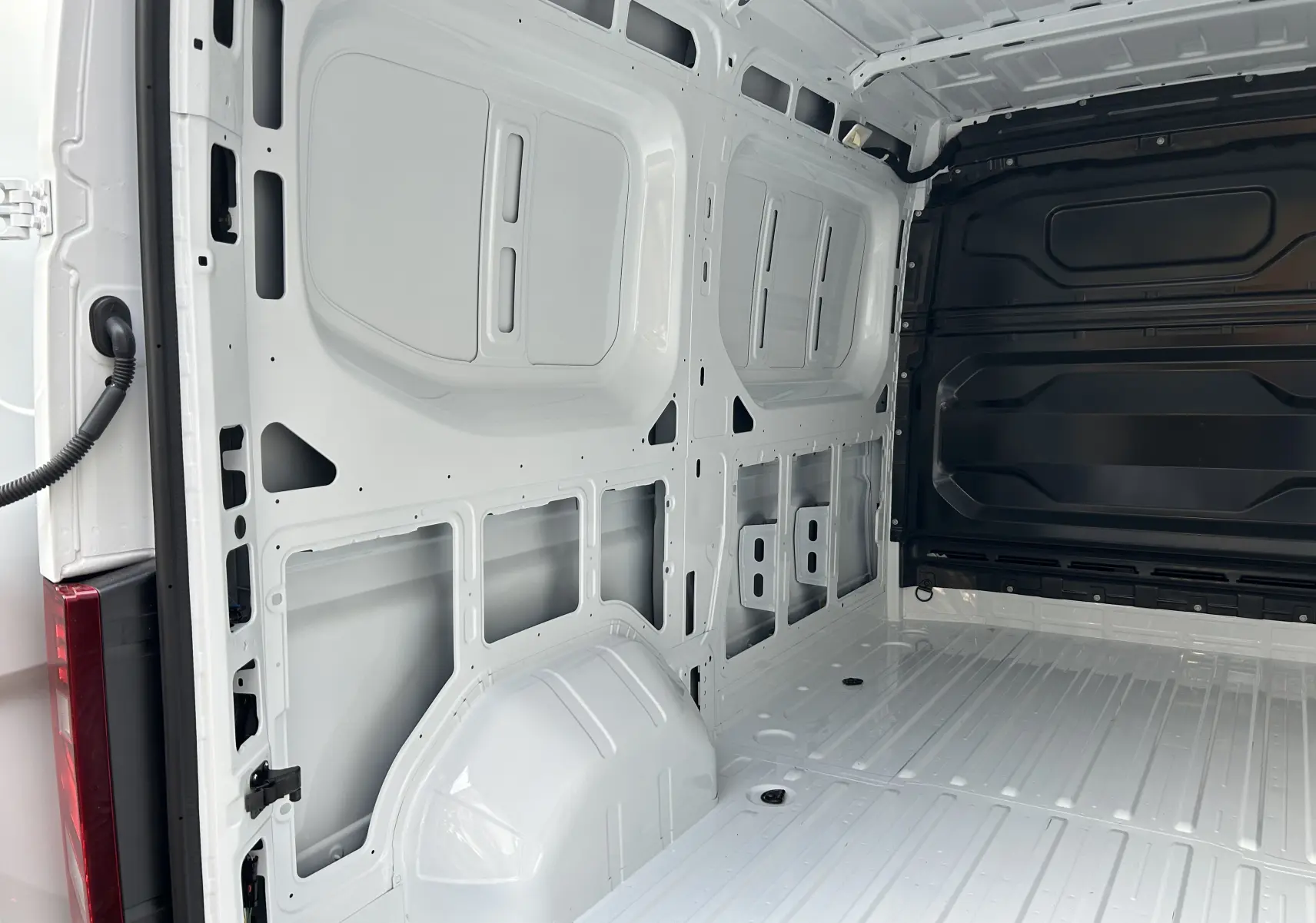 Intérieur du fourgon Renault Master blanc vu côté gauche, montrant la paroi et le plancher métalliques vides.