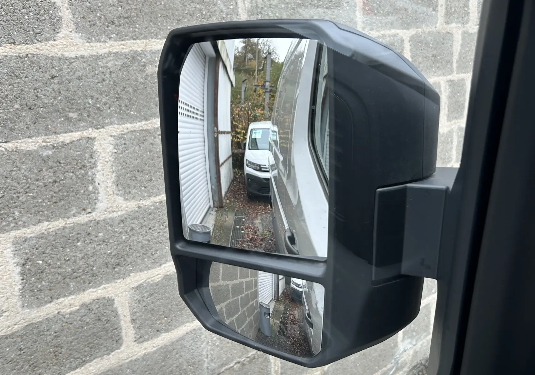 Rétroviseur droit du Renault Master blanc montrant la carrosserie et un autre fourgon blanc en arrière-plan.