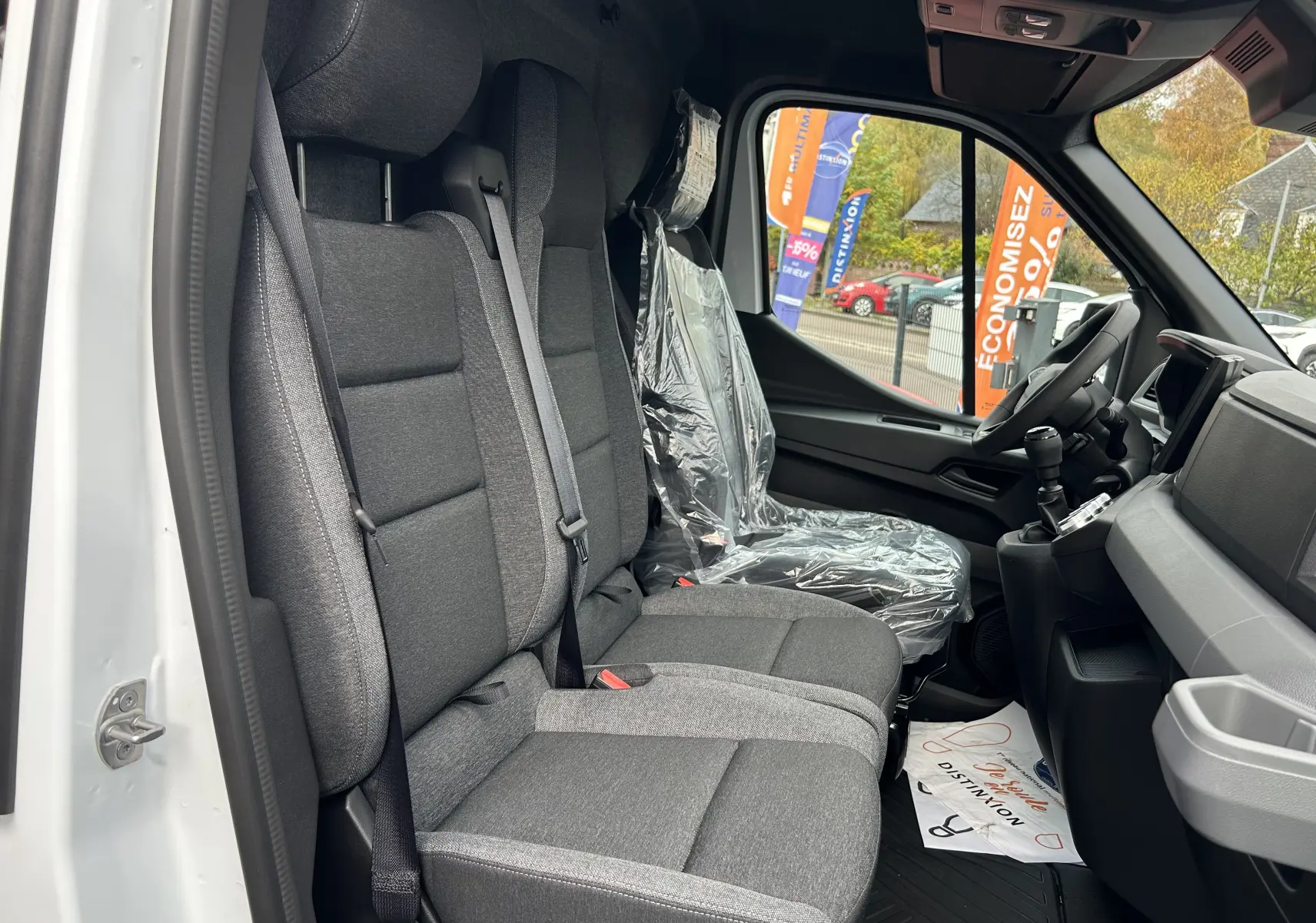 Vue intérieure côté gauche du Renault Master blanc 2026, montrant les sièges gris et le volant avec plastique de protection.