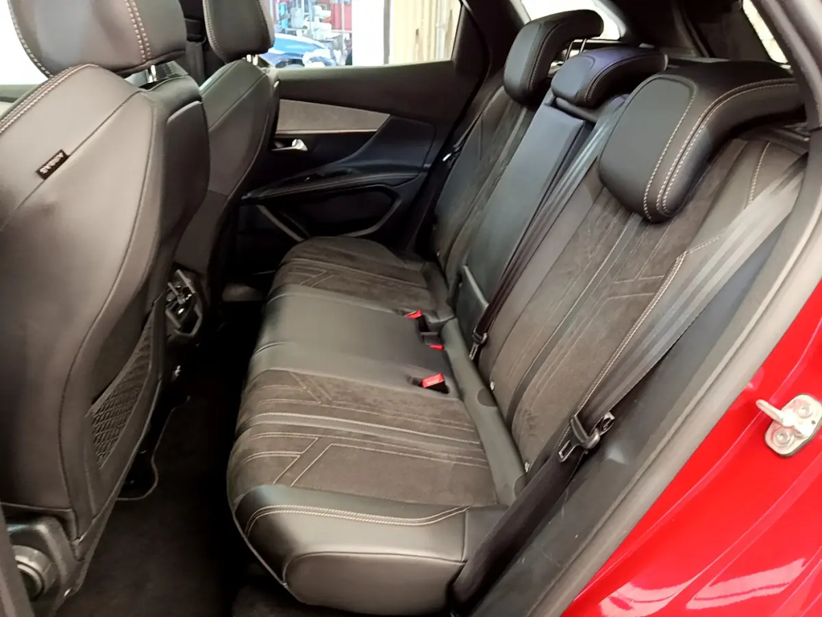 Vue latérale droite de l'intérieur arrière du Peugeot 3008 rouge, avec sièges en cuir et tissu noir.