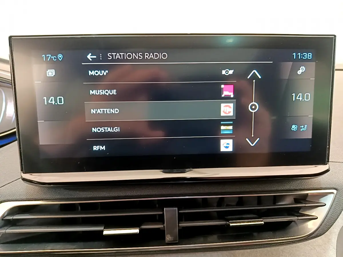 Écran tactile central affichant les stations radio dans l'habitacle du Peugeot 3008 rouge, vue de face.