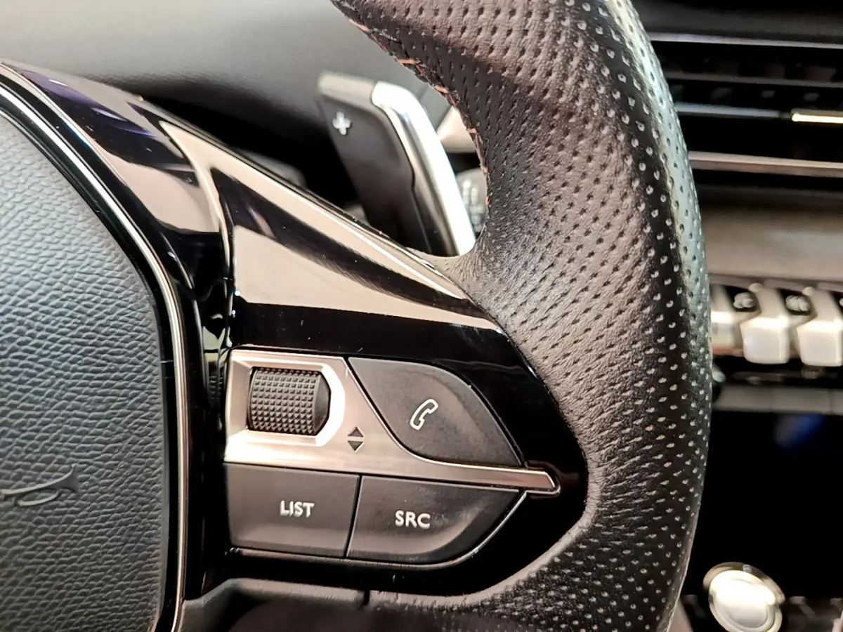Gros plan sur les commandes gauche du volant cuir perforé du Peugeot 3008 GT rouge, avec touches appel et volume.