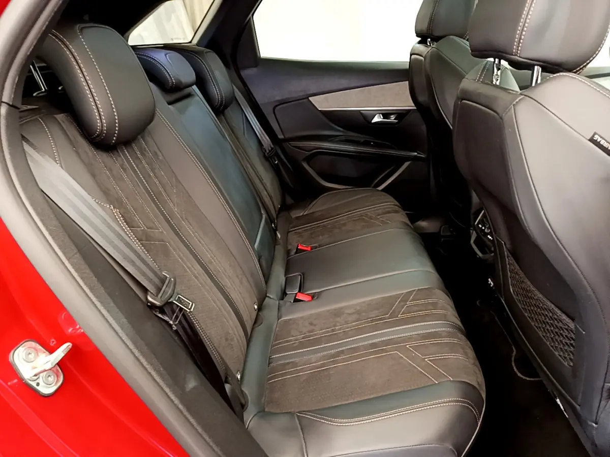 Vue intérieure côté gauche sur la banquette arrière en cuir noir du Peugeot 3008 rouge, avec surpiqûres contrastantes.