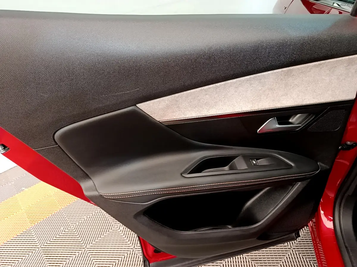Gros plan sur la porte côté gauche rouge du Peugeot 3008 avec garniture noire et bouton de vitre électrique.
