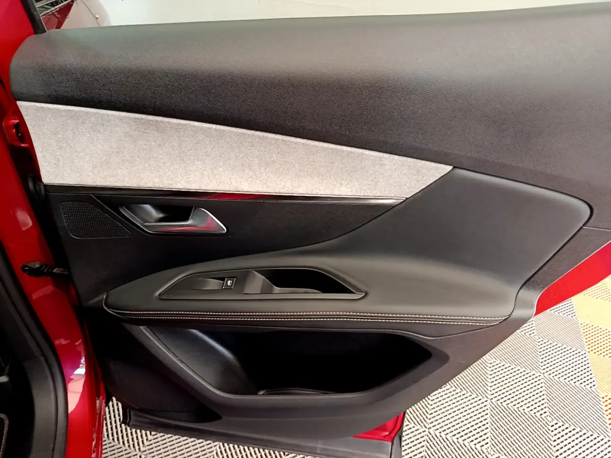 Gros plan sur la porte intérieure côté gauche rouge du Peugeot 3008 GT avec garniture noire et grise.
