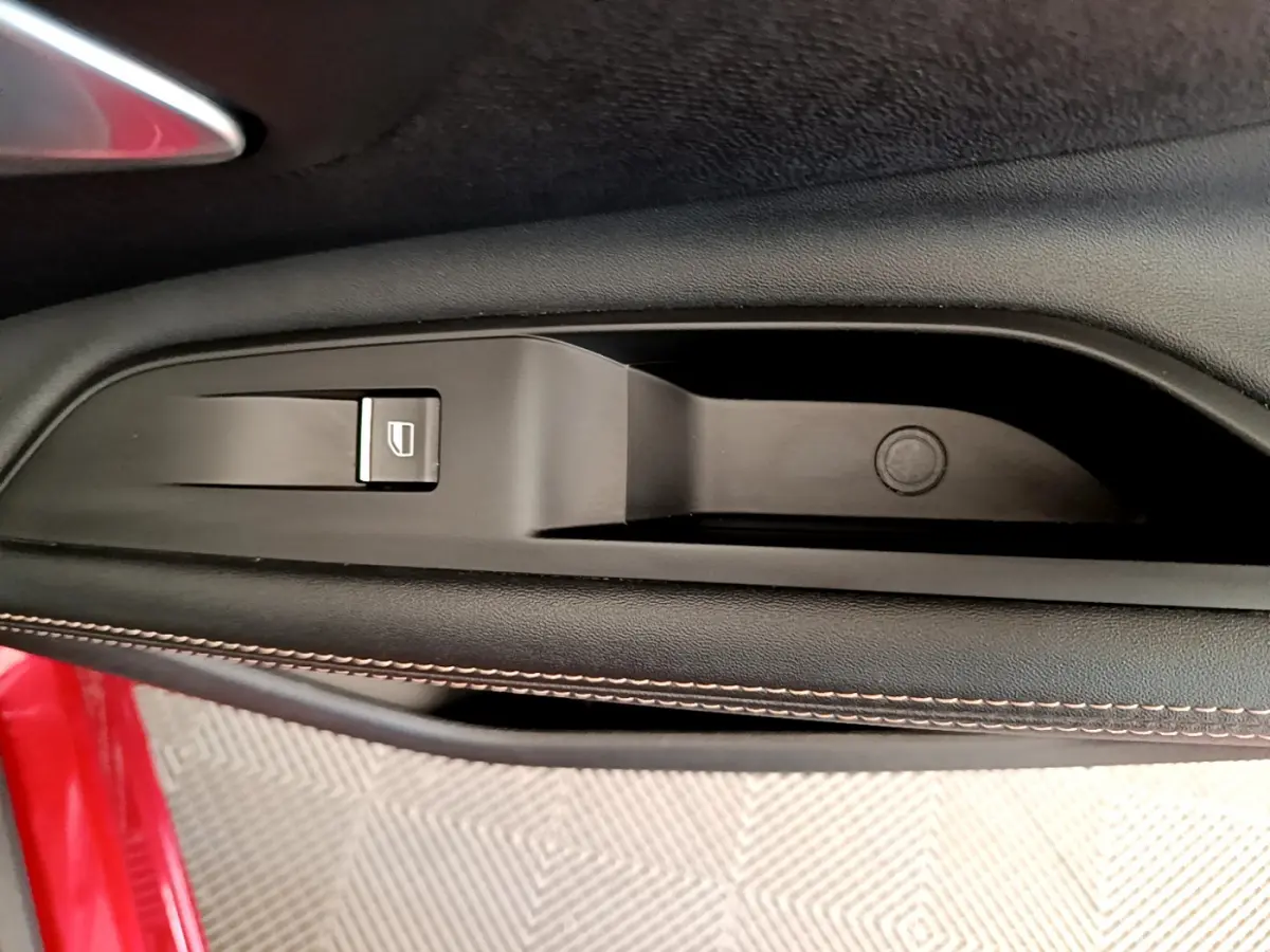 Détail de la commande de lève-vitre sur la porte côté gauche d’un Peugeot 3008 rouge 2021.