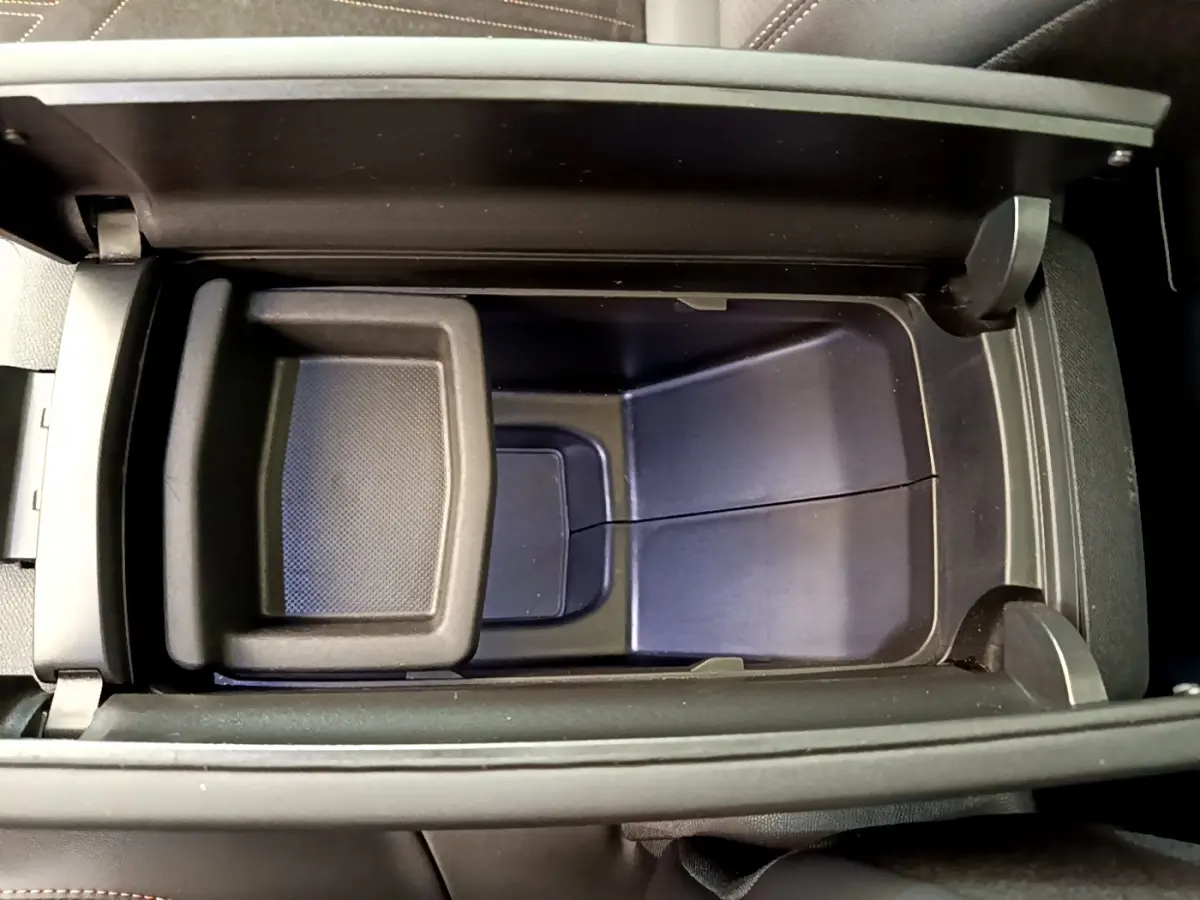 Vue plongeante sur le rangement central noir ouvert de la Peugeot 3008 GT rouge, mettant en valeur son espace intérieur.