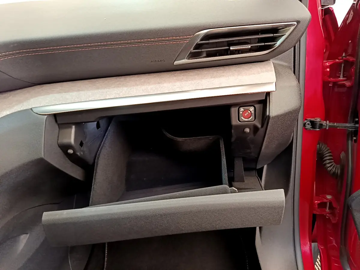 Intérieur du Peugeot 3008 GT 2021 rouge, vue côté passager avec boîte à gants ouverte et tableau de bord noir.