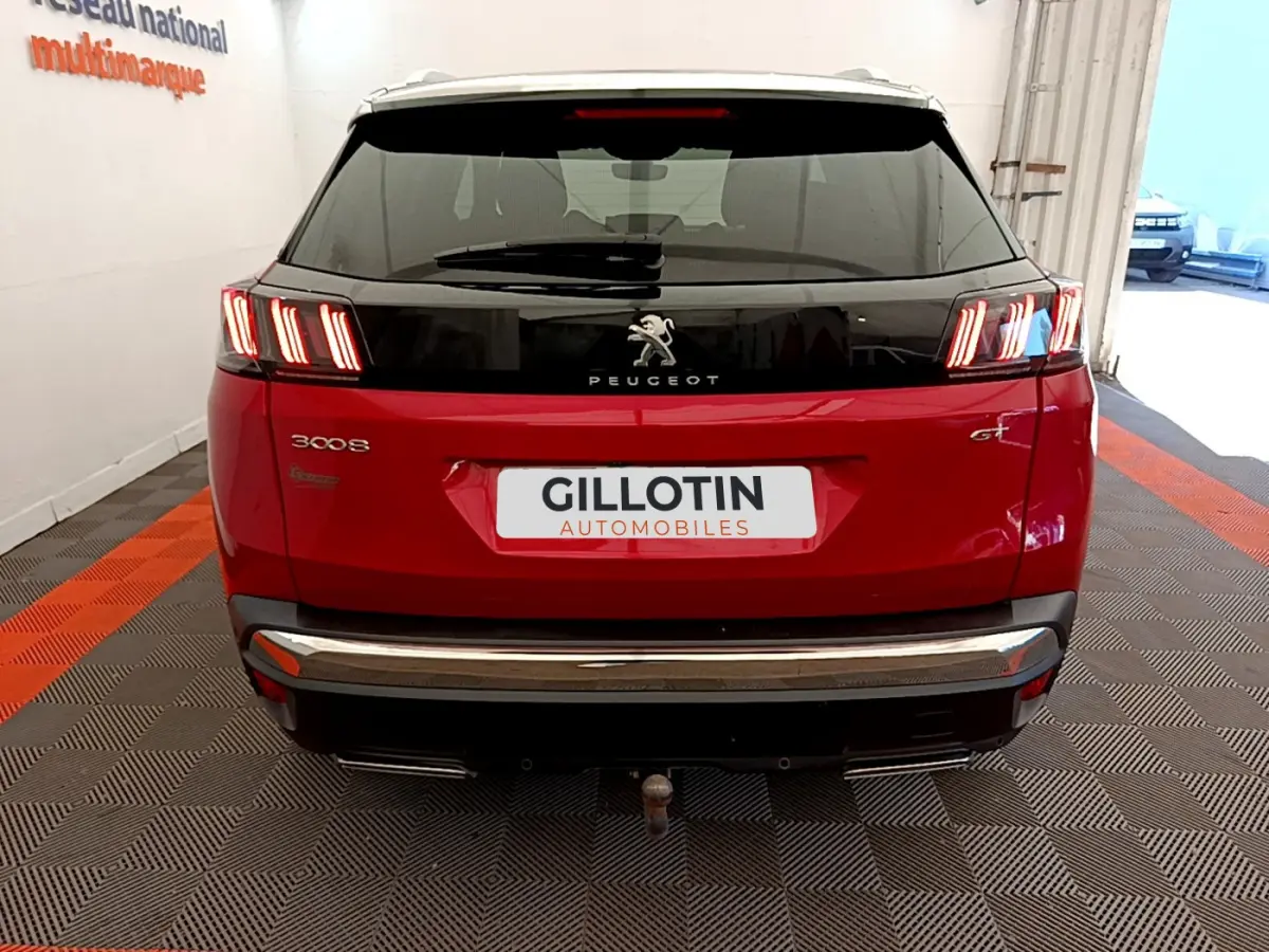 Vue arrière d'un Peugeot 3008 GT rouge avec feux LED distinctifs et attelage visible en intérieur showroom.