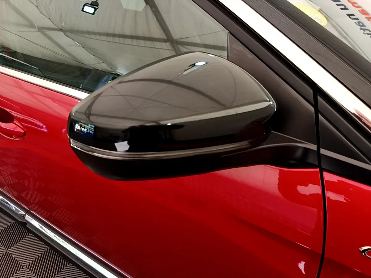 Rétroviseur noir brillant côté gauche sur porte rouge vif d’un Peugeot 3008 GT 2021, vue rapprochée.