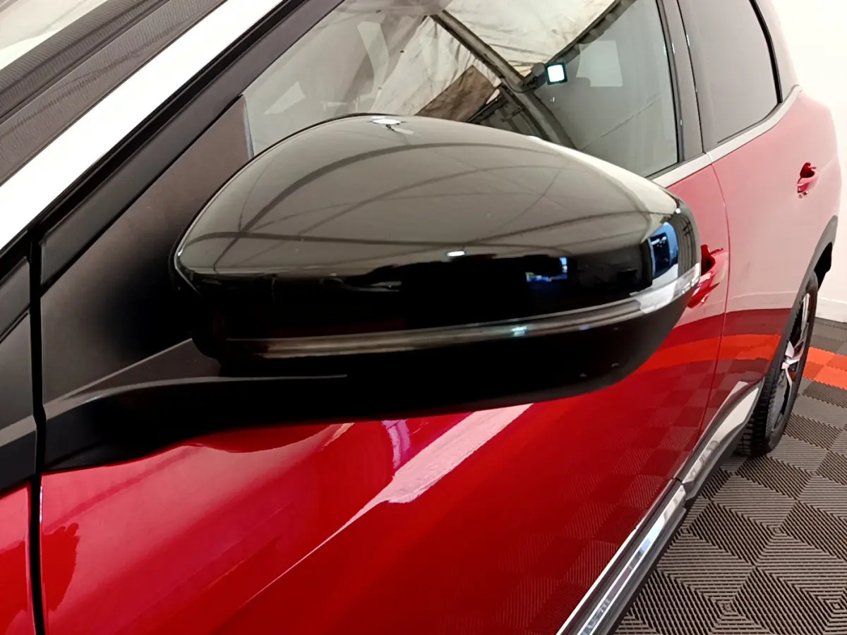 Rétroviseur noir en gros plan côté gauche sur Peugeot 3008 rouge, avec porte et jante partiellement visibles.