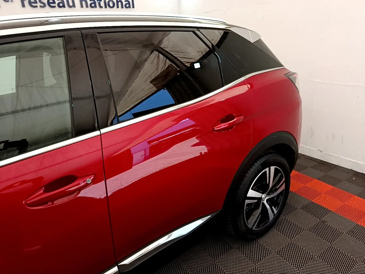 Vue côté droit arrière du Peugeot 3008 GT rouge avec jante alliage et vitrage teinté dans un garage.