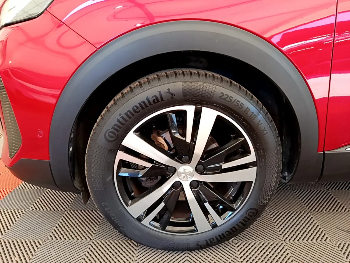 Gros plan sur la roue avant gauche rouge du Peugeot 3008 GT avec jante alliage bicolore et pneu Continental.