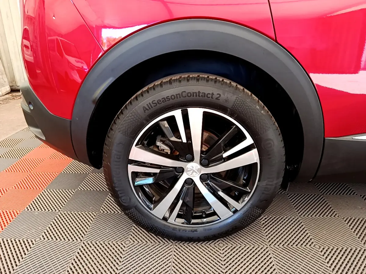 Gros plan sur la roue arrière droite d’un Peugeot 3008 rouge, avec jante alliage bicolore et pneu Continental.