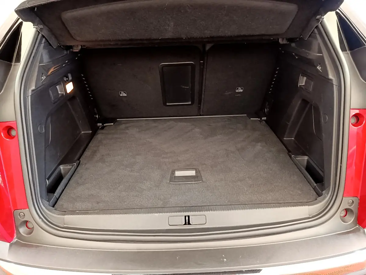 Coffre ouvert d'un Peugeot 3008 rouge, vue arrière montrant un espace de chargement spacieux et tapis noir.
