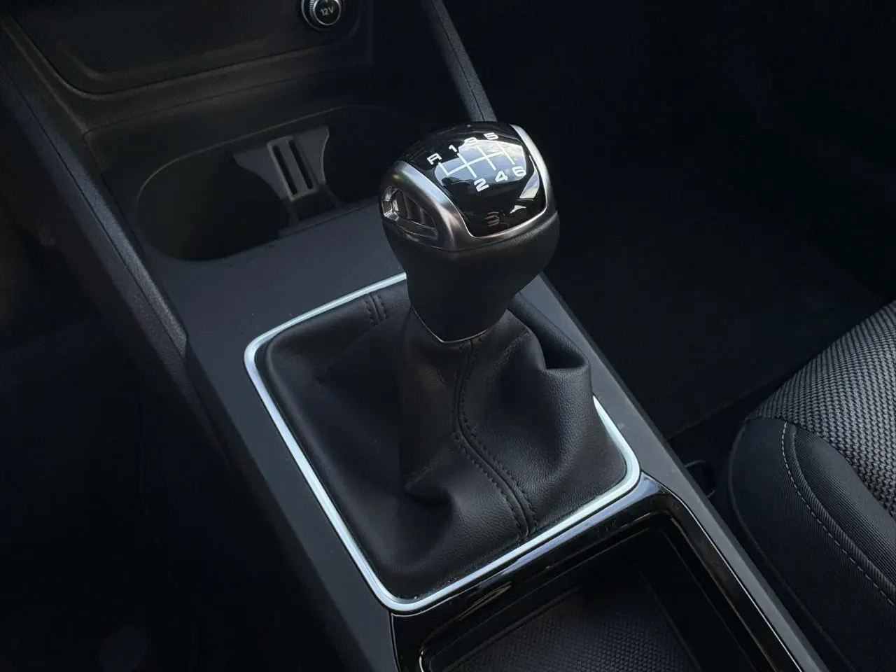 Gros plan sur le levier de vitesses manuel noir de l'Audi Q2 30 TDI 116 S-Line, avec coutures apparentes.