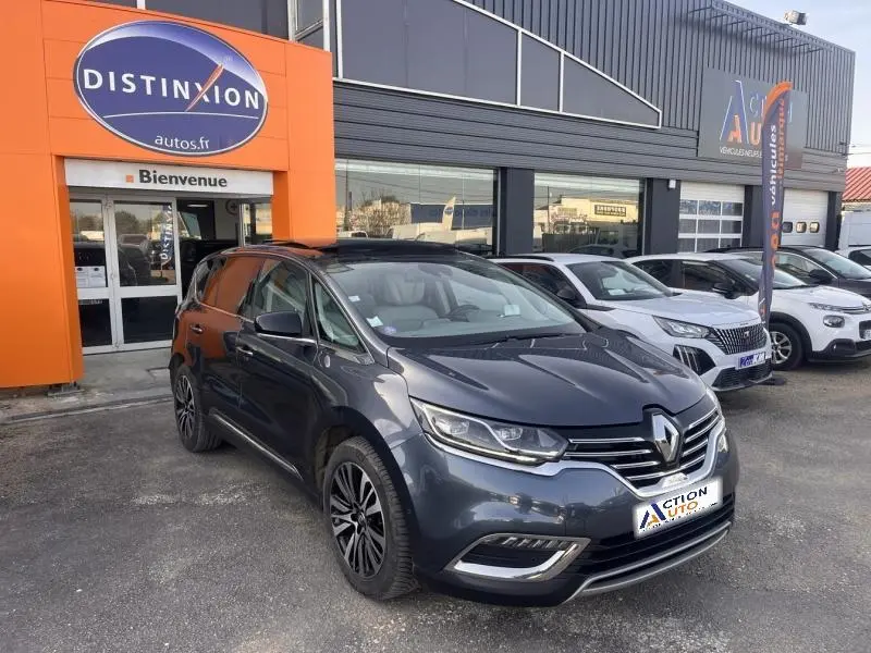 Renault Espace gris Cassiopée vue 3/4 avant droit, avec jantes alliage et calandre chromée, devant un garage.